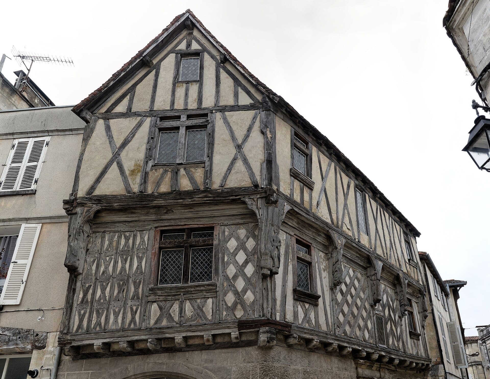 Façade à colombages de la maison de la Lieutenance, à l'angle d'une rue du vieux Cognac, avec ses fenêtres à petits carreaux et son étage en encorbellement.