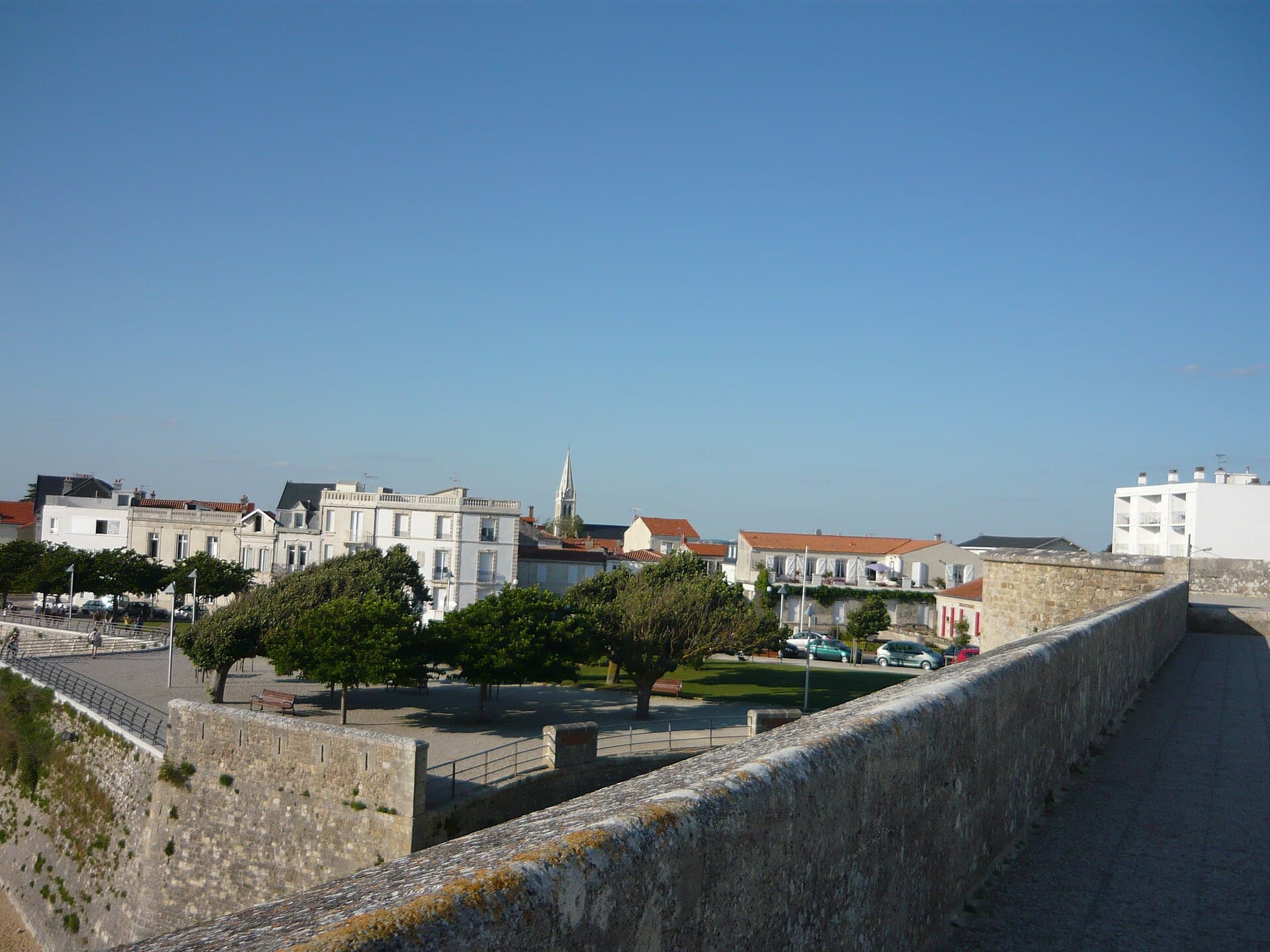 Vue plongeante sur les maisons et les toits de tuiles de Fouras depuis le chemin de ronde du donjon, sous un ciel bleu