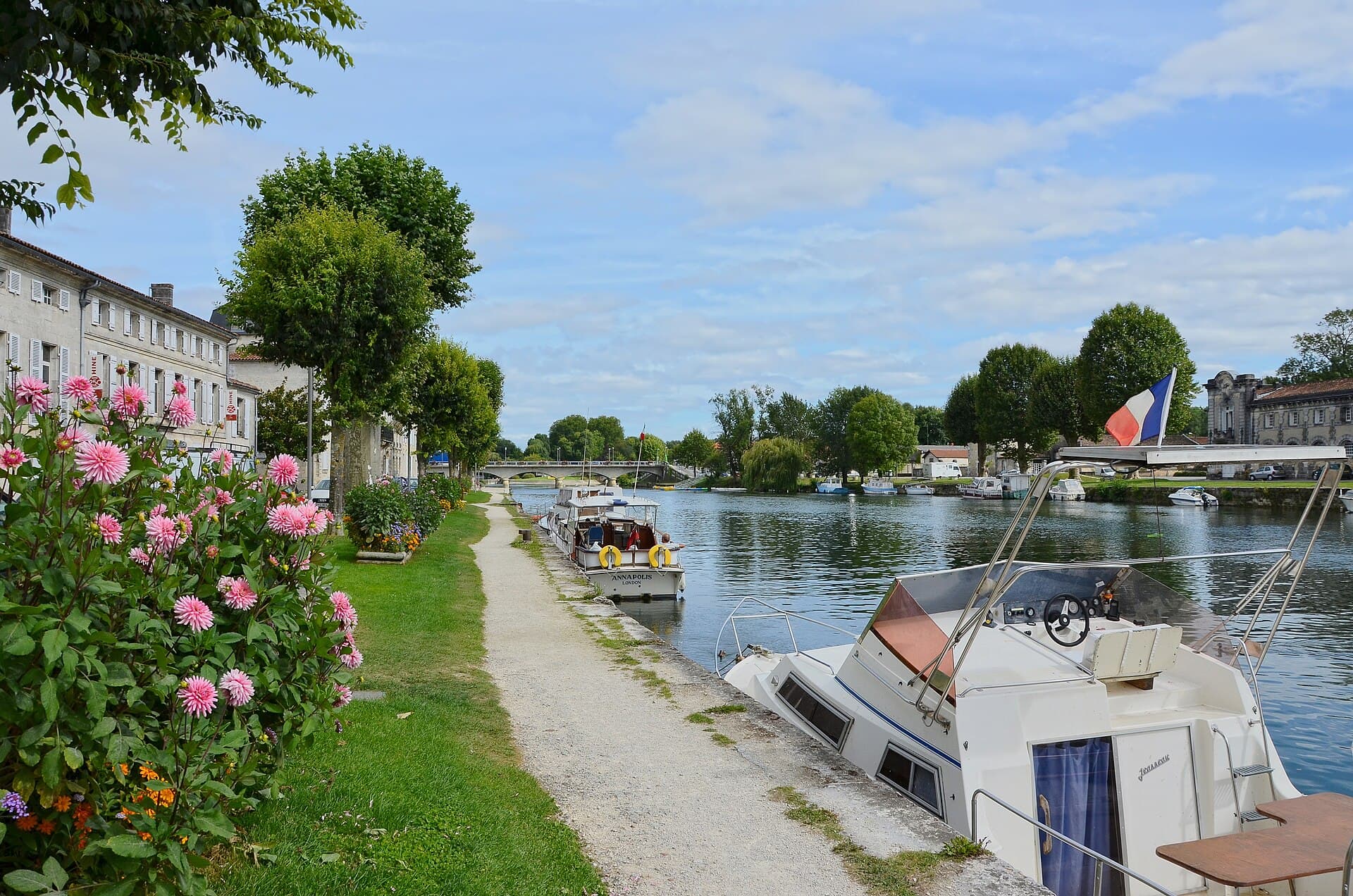 Bateaux de plaisance amarrés le long du quai de l'Orangerie, devant les maisons de Jarnac au bord de la Charente