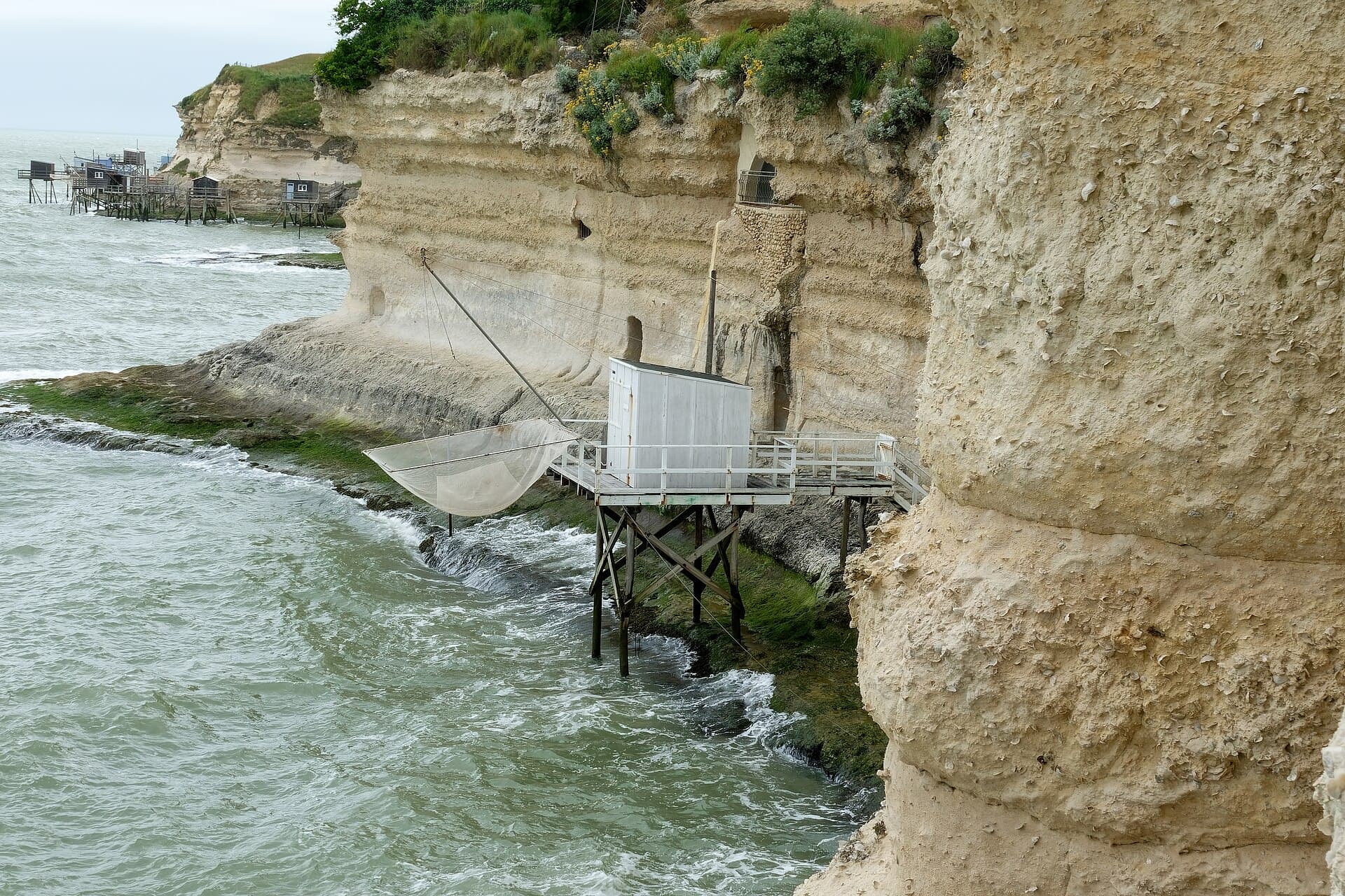 Un carrelet sur pilotis accroché au pied des falaises de calcaire blanc de Meschers-sur-Gironde, au-dessus des eaux de l'estuaire de la Gironde.
