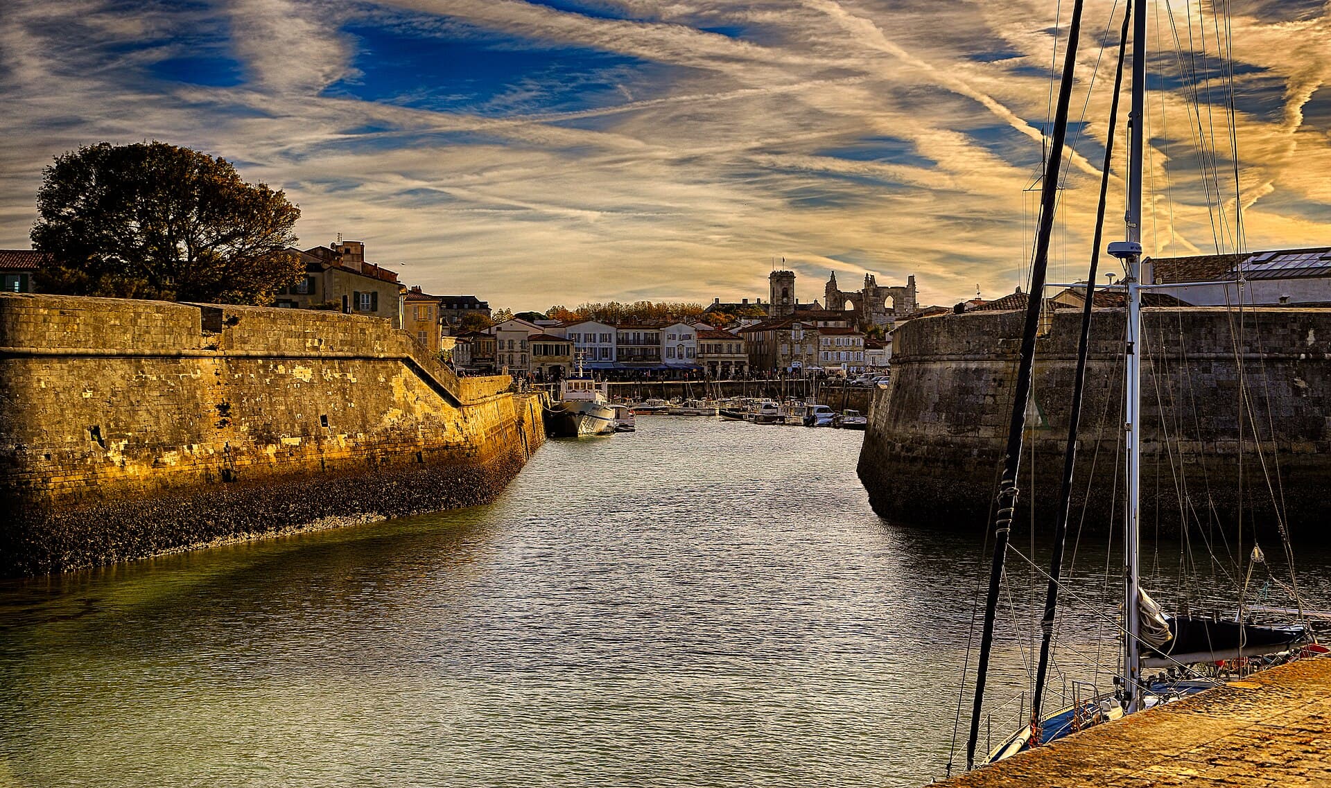 Entrée fortifiée du port de Saint-Martin-de-Ré en fin de journée, avec les maisons du quai et les bateaux en arrière-plan