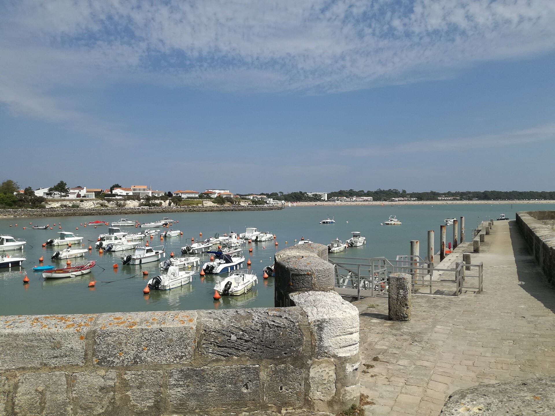 Les bateaux au mouillage dans le port de plaisance de Saint-Georges-de-Didonne, avec le quai en pierre et les maisons du front de mer à l'arrière-plan.